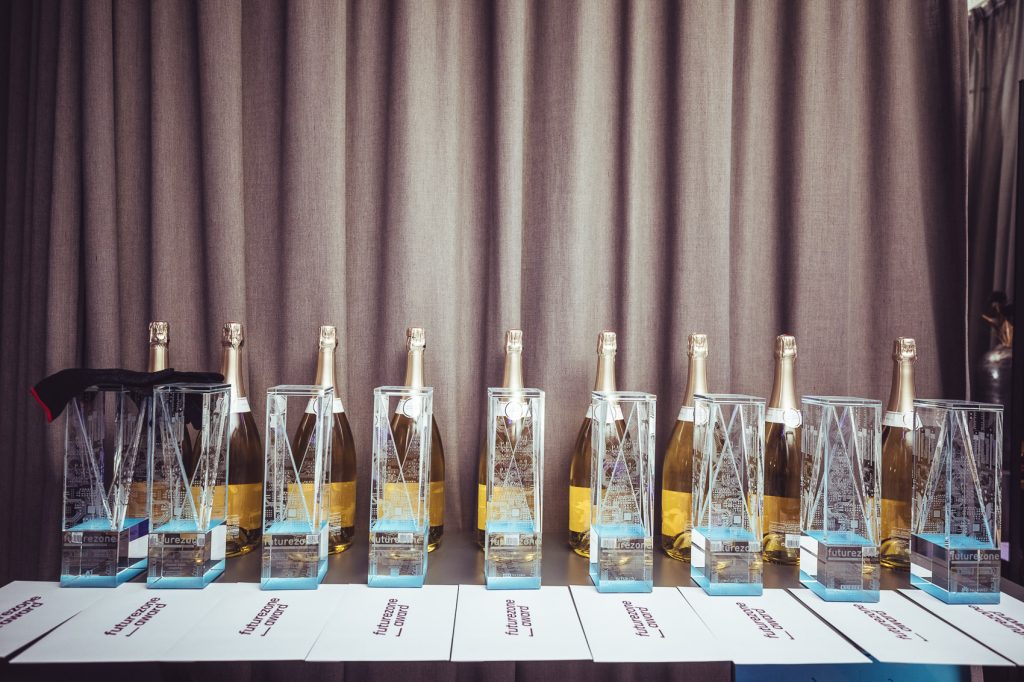 Row of champagne bottles in clear geometric ice holders on a table, with white cards in front and a brown curtain backdrop.