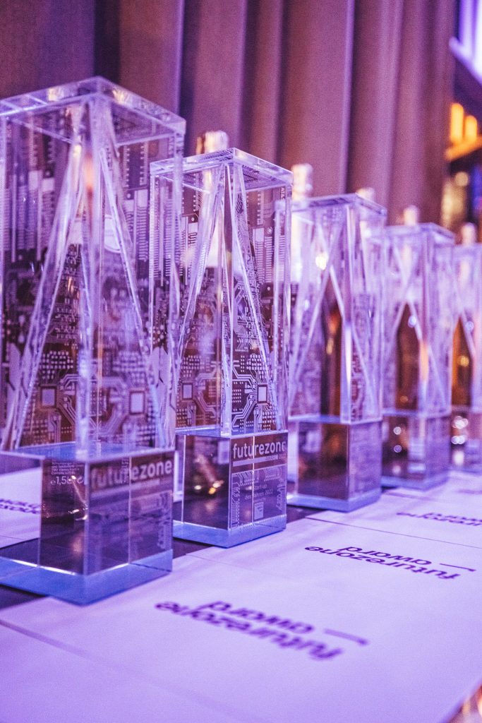 Row of transparent acrylic display blocks containing circuit boards, set on a table under purple lighting.